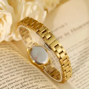 Vue détaillée du bracelet de montre en acier inoxydable doré sur un livre.
