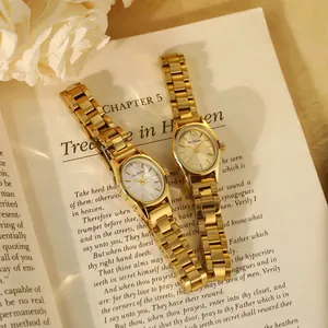 Gros plan de deux élégantes montres dorées en acier pour femmes sur un livre