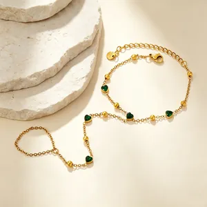 Bracelet bague élégant avec breloques cœur vert et perles dorées sur fond de pierre