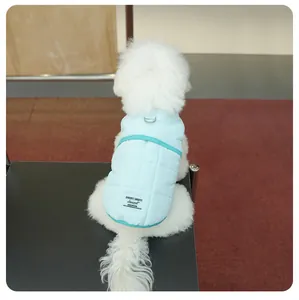 Close-up detail of a light blue quilted dog winter vest showing the integrated harness D-ring