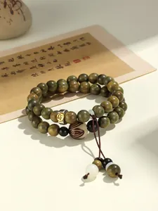 Close-up detail of green sandalwood double-strand bracelet with zodiac metal bead.