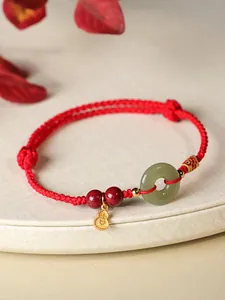 Vue détaillée du bracelet tressé rouge avec beignet de jade et charms gourde dorée.