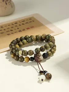 Detailed close-up of green sandalwood double-strand bracelet with carved charm beads