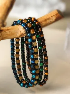 Detalle de pulseras de cuentas de ojo de tigre de 4 mm en tonos azul, oro y verde en rama.