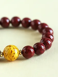 Nahaufnahme eines natürlichen Zinnober-Kristallperlenarmbandes mit goldener Akzentperle.