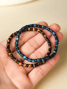 Primer plano de pulseras de cuentas de ojo de tigre amarillo y azul de 4 mm en la mano.