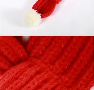 Detail showing the soft texture and white pom-pom of the warm red knitted pet scarf.