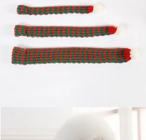 Set of three red and green striped knitted pet scarves with white pom-poms for Christmas