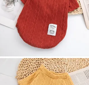 Detailed view of red and yellow cable knit pet sweaters with cute bear patch