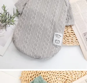 Close-up detail of grey cable knit pet sweater featuring Lucky Bear patch texture