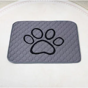 Detalle del empapador reutilizable gris para mascotas con diseño de huella negra
