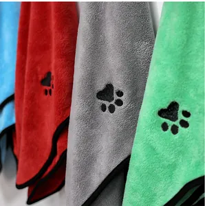 Macro view of soft absorbent coral fleece pet towels featuring cute embroidered paw prints