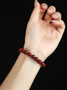 Detailansicht eines eleganten Armbands aus dunkelroten Zinnoberperlen am Handgelenk