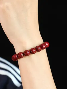 Nahaufnahme eines Armbands aus natürlichen roten Zinnoberperlen mit Kristallstruktur.
