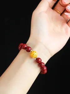 Detailansicht eines natürlichen roten Zinnober-Armbands mit gelber Perle am Handgelenk.