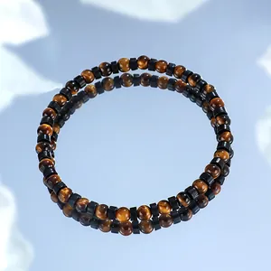 Pulsera minimalista de cuentas de ojo de tigre de 4mm sobre una superficie de espejo