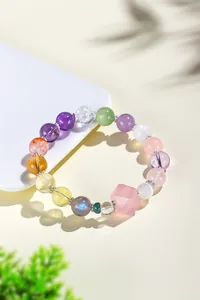 Primer plano de una pulsera de cristal multicolor con una gran piedra rosa hexagonal.
