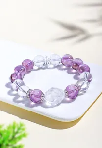 Primer plano detallado de una pulsera de cristal natural con cuentas púrpuras y claras talladas