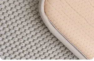 Détail d'un tapis antidérapant pour animaux avec surface grise texturée et base beige.