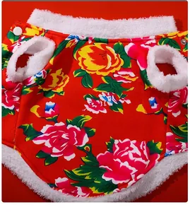 Close-up detail of festive red pet jacket with floral pattern and fleece trim.