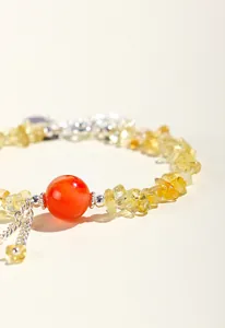 Dettaglio di braccialetto in citrina naturale con una pietra centrale di agata rossa