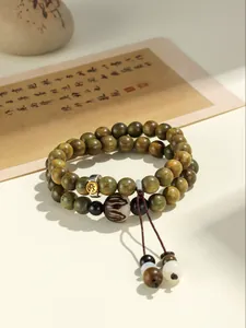Detailed view of a double-strand green sandalwood beaded bracelet with carved charm.