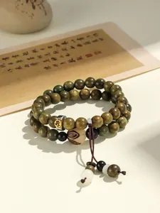 Macro view of a green sandalwood double-strand beaded bracelet with a carved charm