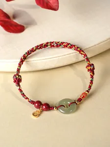 Gros plan d'un bracelet en corde rouge fait main avec jade néphrite et perles de cinabre.