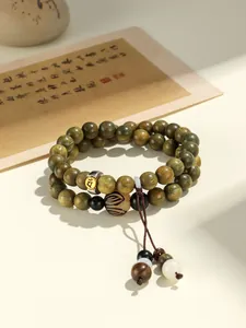 Close-up detail of green sandalwood double-loop beaded bracelet with carved Buddha charm