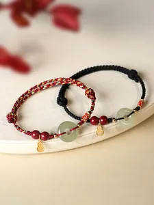Gros plan détaillé de bracelets ethniques tissés main avec pendentifs en jade et or.