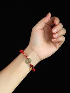 Vue détaillée d'un bracelet en corde rouge fait main avec pendentif jade et perles cinabre