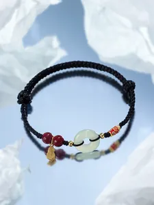 Gros plan d'un bracelet tressé à la main avec boucle de sécurité en jade et perles de cinabre