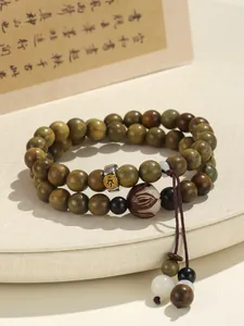 Detailed macro view of a green sandalwood double strand beaded bracelet with spiritual charms.