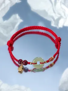 Vue détaillée du bracelet rouge tissé avec beignet en jade Hetian et breloques.