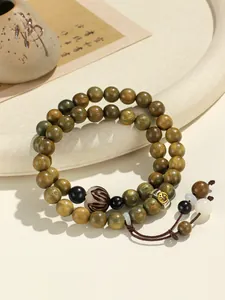 Detail of green sandalwood double-loop bracelet with carved beads and golden charm.