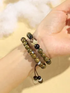 Close-up of double-layered green sandalwood beaded bracelet with carved zodiac patterns