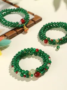 Macro view of multi-layer green and red agate beaded bracelets with delicate charms