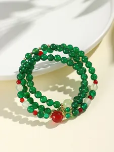 Macro view of green and red agate multi-layer beaded bracelet with small gold charm