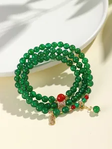 Detail view of green agate beaded bracelet with a lucky gold charm and red accents.