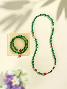 Detail shot of green and red agate beaded necklace and bracelet set on beige background