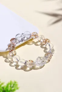 Primer plano de pulsera de cuarzo transparente y rutilado con dije de tortuga dragón tallada.