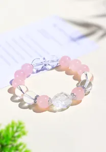 Primer plano detallado de una pulsera de cristal rosa con una tortuga dragón tallada.