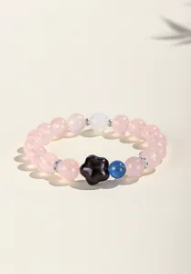 Vista detallada de pulsera de cuarzo rosa con dije de estrella de obsidiana negra.
