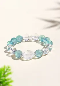 Primer plano de una pulsera de fluorita y cuarzo transparente con un dije de tortuga dragón