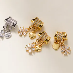 Close-up of gold and silver flower heart charms with inlaid rhinestones for DIY jewelry.