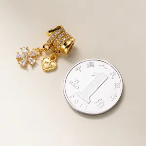 Close-up view of the 925 silver flower and heart charm next to a coin for scale reference.