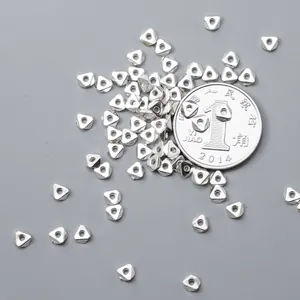 Macro detail of 925 sterling silver triangle beads with coin for size reference.