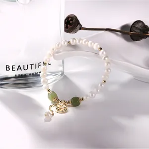 Detailed shot of a freshwater pearl bracelet with green jade beads and fortune charm