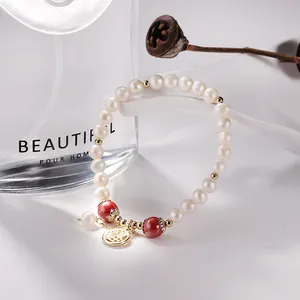 Detailed macro view of handmade freshwater pearl bracelet with red beads and gold charm