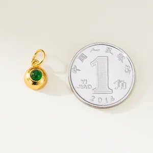 Gros plan d'un pendentif en argent doré avec incrustation d'émeraude près d'une pièce